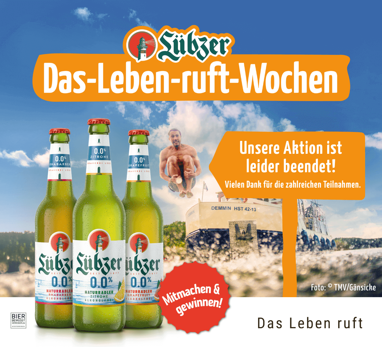 Drei Flaschen Lübzer Naturradler Akoholfrei. Im Hintergrund ist ein Hausboot mit Menschen abgebildet.