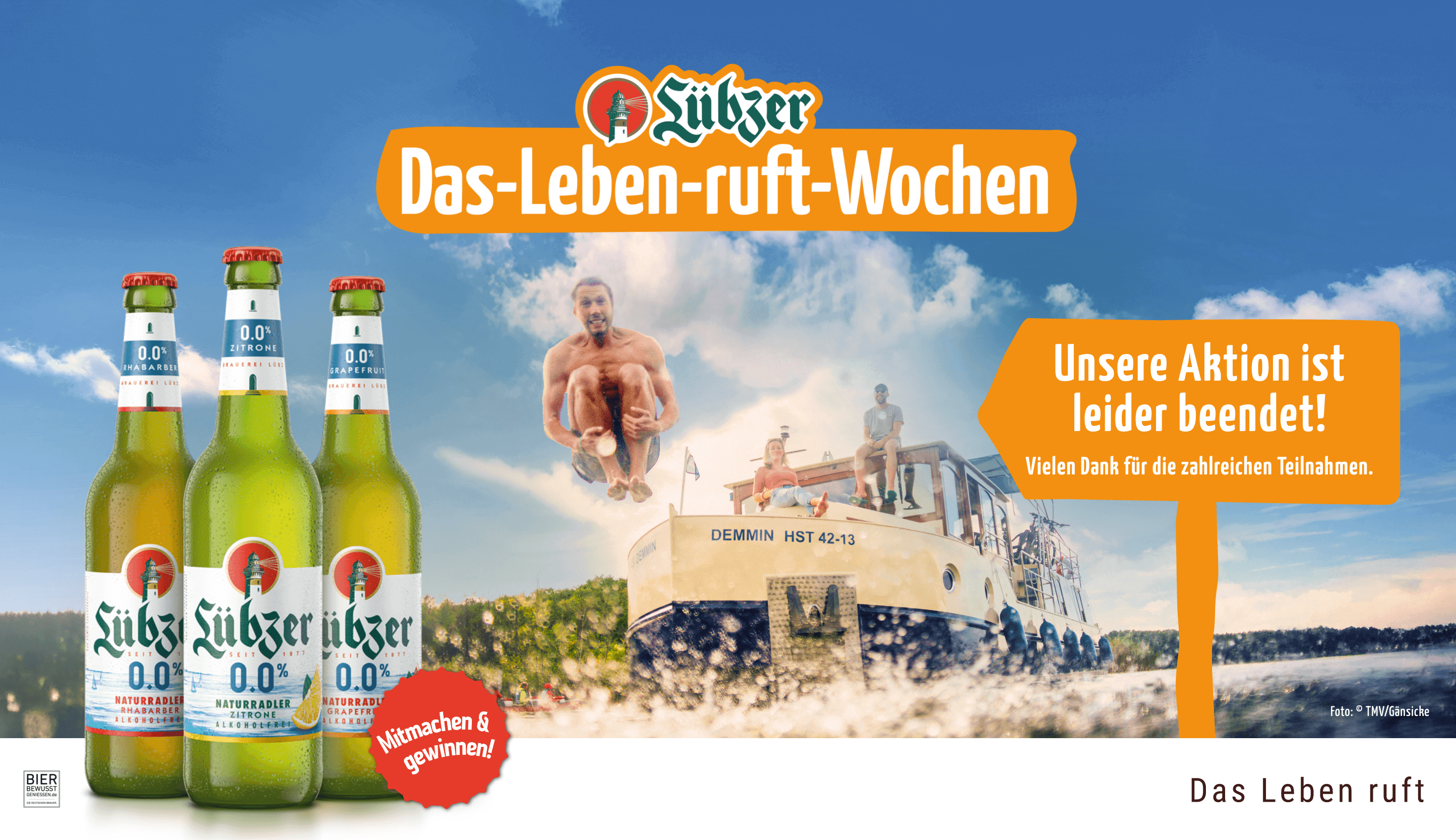 Drei Flaschen Lübzer Naturradler Akoholfrei. Im Hintergrund ist ein Hausboot mit Menschen abgebildet.